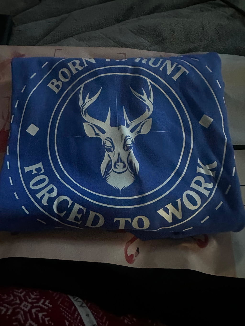 Blue t-shirt with a deer emblem reading Born to hunt, forced to work, from a customer review